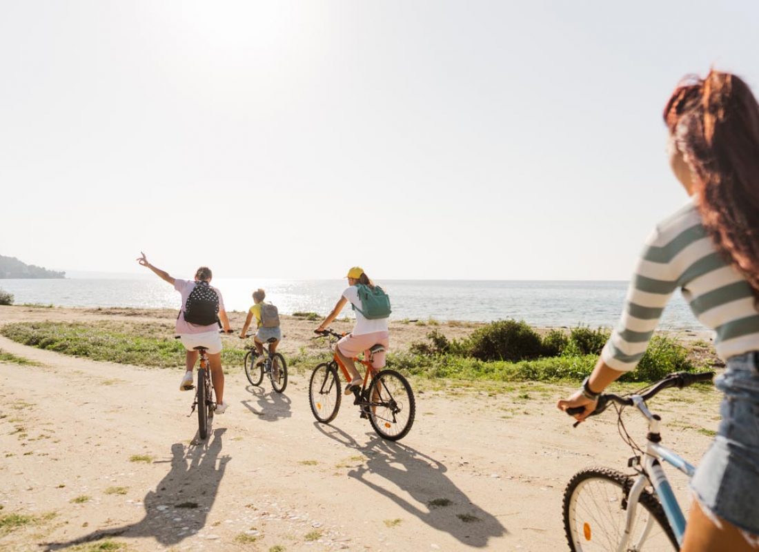 Photo of a smiling teenage girls, using bicycles to commute to the beach