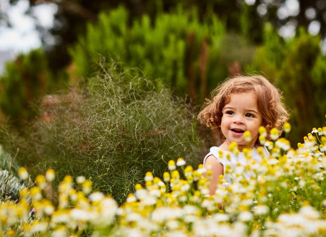Shot of a cute little girl looking at flowers in a garden
